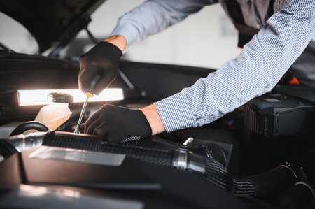 Friendly mechanic in modern car repair shop with car. Professional technician checking vehicle diagnostics and maintenance. Concept of automotive industry and customer service.の写真素材