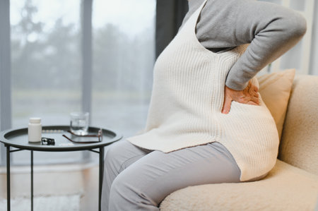 Senior woman suffering from back pain at home.