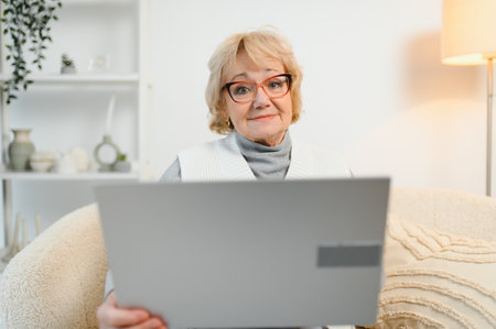 Resourceful mature smiling woman using laptop at home.