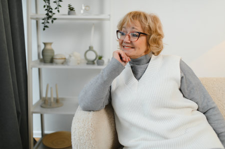 Comfort relaxed old senior elderly woman grandmother at home looking at camera in the living room. Pension concept.の写真素材