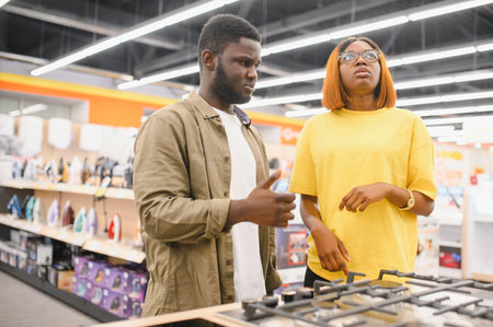 Young african american family couple buying new gas stove in supermarket.の写真素材