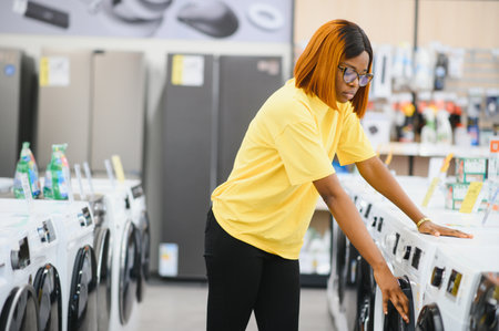 A young woman in a store chooses a washing machine.. The concept of shopping.の写真素材