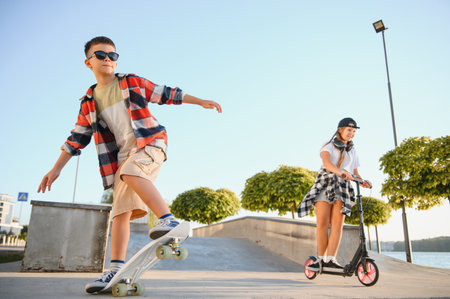 Happy kids having fun at the skate park. Concept of summer holidays and recreation.