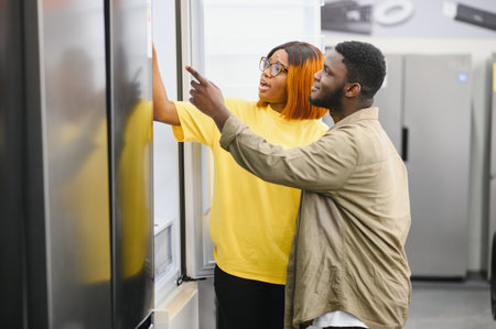 Young man and woman are choosing a refrigerator in an appliance store. Cyber Monday concept.の写真素材