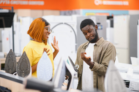 Couple standing in an electronics store choosing an electric iron for Ironing things, household choresの写真素材