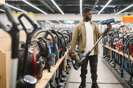 An African American man chooses a new model of vacuum cleaner in an electronics store.