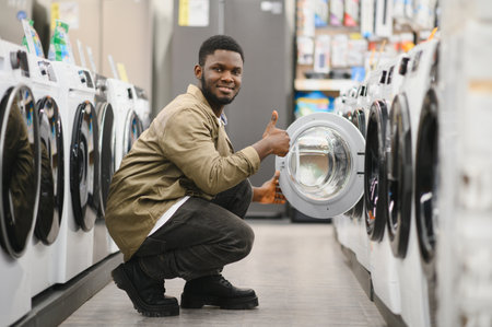 Household appliances store. An African American man buys a new modern washing machine.の写真素材