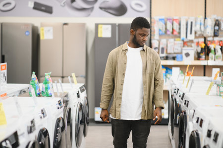 Household appliances store. An African American man buys a new modern washing machine.の写真素材