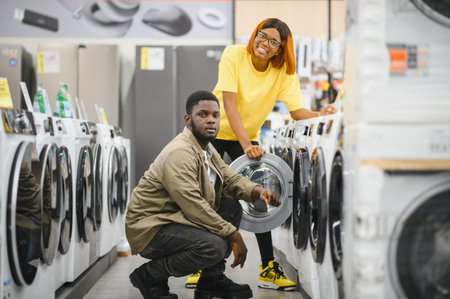 African American Couple choosing washing machine at electronics store.
