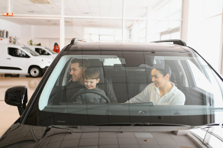 A joyful family sitting inside a new car at a dealership, with parents and child excitedly exploring...