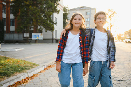 Happy school kids friends boy and girl with backpacks walking and laughing having fun together near...