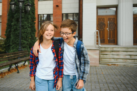 Happy school kids friends boy and girl with backpacks walking and laughing having fun together near...
