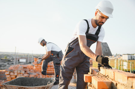 Construction worker man in work clothes and a construction helmet. Portrait of positive male builder in hardhat working at construction site.の写真素材