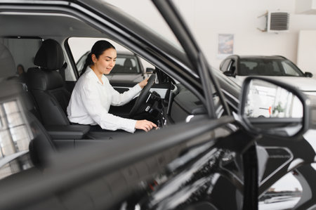 Beautiful girl looking through the car window. Business woman choosing new car in car dealership.