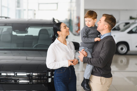 Young happy family enjoying while buying a new car in a showroom.の写真素材