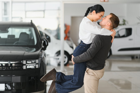 Beautiful young couple at car showroom exited because of buying a new car.の写真素材