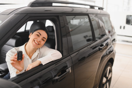 Beautiful girl looking through the car window. Business woman choosing new car in car dealership.