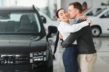 Woman hugging her husband, standing near new car.の写真素材