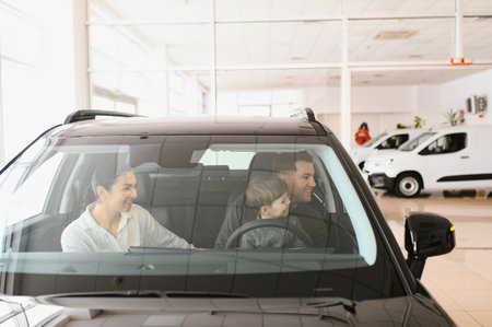 Family in a car dealership. Happy family came to an agreement with a car salesperson at a meeting in a showroom. Happy family choosing a new car in a showroomの写真素材