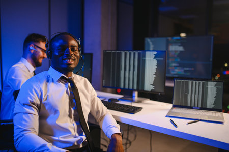 Happy Confident Technical Customer Support Specialist Having a Headset Call in a Monitoring and Control Room Filled with Colleagues and Display Screens.の写真素材