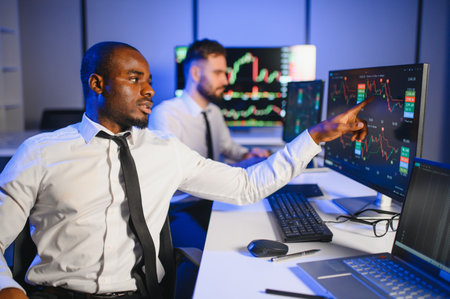 Two businessmen, financial analysts or investment advisers sitting at office desk with computers and...