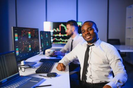 Conception of teamwork. Team of stockbrokers works in modern office with many display screens.