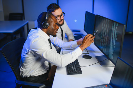 Male Data Scientist Works on Personal Computer Wearing a Headset in Big Infrastructure Control and...