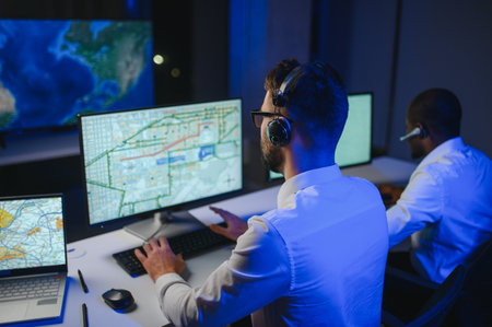 Center of dispatching maintenance. Portrait of men working via headset microphone while sitting on...