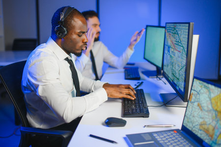 Center of dispatching maintenance. Waist up side on of young Afro-American males working on air navigation controller boardの写真素材
