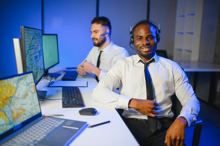 Center of dispatching maintenance. Waist up side on of young Afro-American males working on air navigation controller boardの写真素材