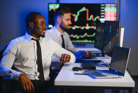 Conception of teamwork. Team of stockbrokers works in modern office with many display screens.