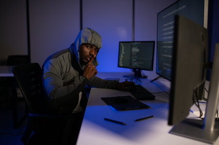 African american Hacker with computer, man sitting at a table in a hoody.の写真素材