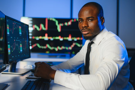African american male stock trader or broker working at stock exchange office using computer on...