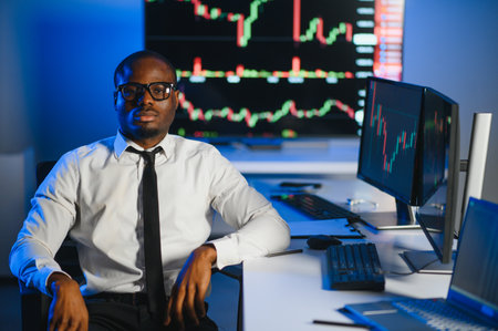 African american male stock trader or broker working at stock exchange office using computer on...