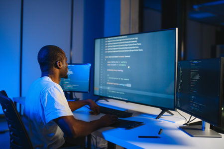 Portrait of African American male programmer in office at night.