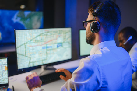 Center of dispatching maintenance. Portrait of men working via headset microphone while sitting on...