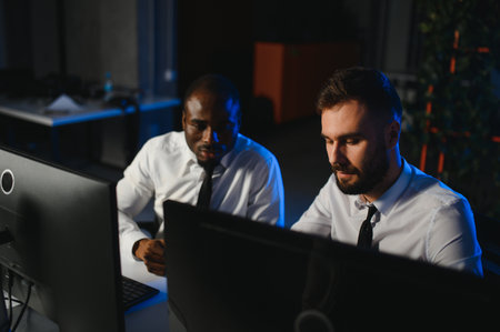 Two businessmen, financial analysts or investment advisers sitting at office desk with computers and documents, business analysisの写真素材