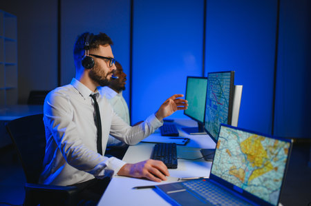 Center of dispatching maintenance. Portrait of men working via headset microphone while sitting on navigation controller board.の写真素材