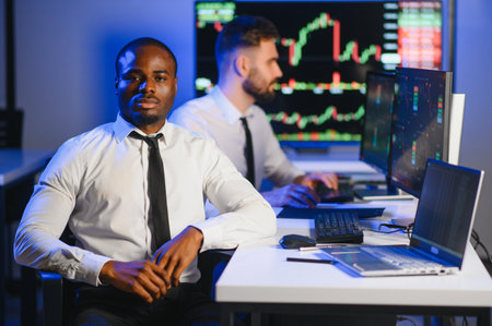 Conception of teamwork. Team of stockbrokers works in modern office with many display screens.の写真素材