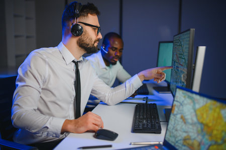 Center of dispatching maintenance. Portrait of men working via headset microphone while sitting on...
