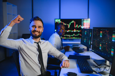 Two businessmen, financial analysts or investment advisers sitting at office desk with computers and documents, business analysisの写真素材