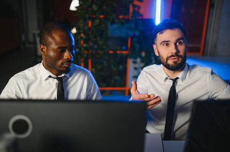 Two businessmen, financial analysts or investment advisers sitting at office desk with computers and documents, business analysisの写真素材