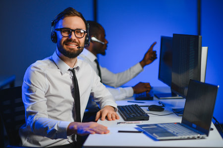 Happy Confident Technical Customer Support Specialist Having a Headset Call in a Monitoring and Control Room Filled with Colleagues and Display Screens.の写真素材
