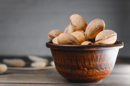 Delicious nut shaped cookies with boiled condensed milk on a wooden background.