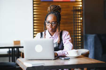 Portrait of an African American young woman sitting at cafe with laptop writing her blog.