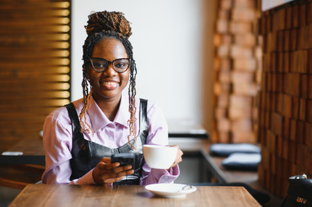 Young african woman using smart phone in a modern cafe.の写真素材