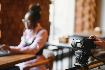 Young blogger with laptop recording video on camera at cafeの写真素材