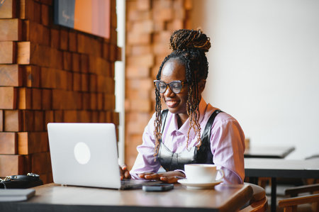 Focused young African woman sitting alone at a counter in a cafe.の写真素材