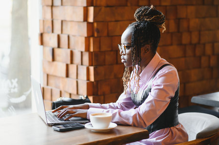 Focused young African woman sitting alone at a counter in a cafe.の写真素材