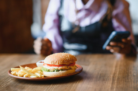 African woman with afro hair eating a tasty classic burger with fries. Cheat Meal.の写真素材
